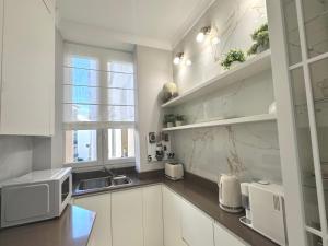 een witte keuken met een wastafel en een magnetron bij LUXE PALAIS DE LA MÉDITERRANÉE in Nice