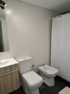 a white bathroom with a toilet and a sink at Nuevo, apartamento completo, parking, en Cordón Soho in Montevideo