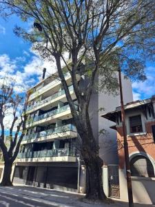 un edificio alto con un árbol delante de él en Nuevo, apartamento completo, opción parking, en Cordón Soho, en Montevideo