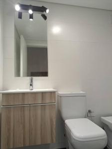 a bathroom with a toilet and a sink and a mirror at Nuevo, apartamento completo, parking, en Cordón Soho in Montevideo