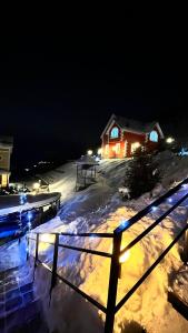 uma casa na neve à noite com luzes em Домик у гор em Besqaynar