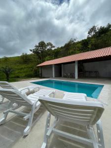 a group of lounge chairs next to a swimming pool at Fazenda Kidauana - Mendes in Mendes