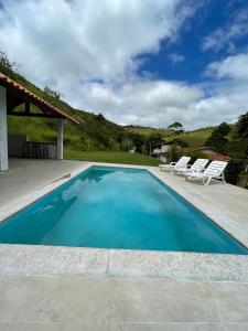 a swimming pool with two lounge chairs and a house at Fazenda Kidauana - Mendes in Mendes