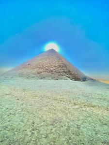 a pyramid in the middle of a field at Happy pyramids view in Kafret el-Gabal
