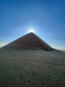 a pyramid in the middle of a field at Happy pyramids view in Kafret el-Gabal
