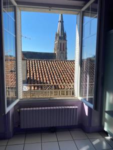 an open window with a view of a church at Les chambres de Marielou in Aurillac