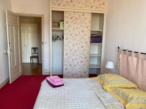 Un dormitorio con una cama con una maleta rosa. en Les chambres de Marielou, en Aurillac