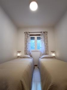 two beds in a room with a window at Apartamento KumiKata in Odemira