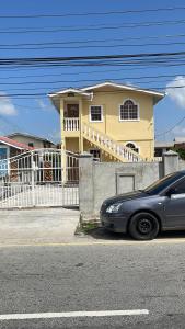 un'auto parcheggiata di fronte a una casa gialla di KSA Apartments a Georgetown