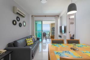 a living room with a couch and a dining room table at Apart hotel a Beira Mar na praia do Recreio in Rio de Janeiro