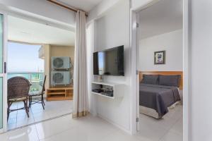 1 dormitorio con 1 cama, TV y balcón en Apart hotel a Beira Mar na praia do Recreio, en Río de Janeiro