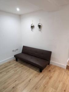 a black couch in a room with a white wall at City Sparrow Apartment 2B in London