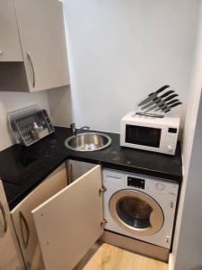 a small kitchen with a microwave and a sink at City Sparrow Apartment 2B in London