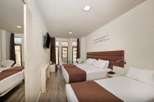 ein Hotelzimmer mit 2 Betten und einem TV in der Unterkunft 1881 Barcelona Gran Rosellon Hotel in Barcelona