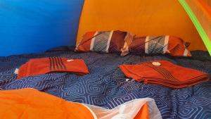 韋韋特南戈的住宿－LA OFFI GT，帐篷内的一张床位,上面有两件红色衬衫