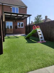 un parque infantil con un tobogán en un patio en Comfy home near airport en Speke