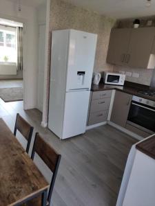 a kitchen with a white refrigerator and a table at Comfy home near airport in Speke