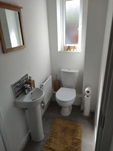 La salle de bains blanche est pourvue de toilettes et d'un lavabo. dans l'établissement Comfy home near airport, à Speke