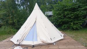 une tente installée au-dessus d'une terrasse en bois dans l'établissement Glamping Fluffy Horns - Glempings Pūkainie Ragi, à Plieņciems