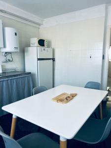 uma cozinha com uma mesa branca com cadeiras e um frigorífico em Departamento Moya 25 em Bragado
