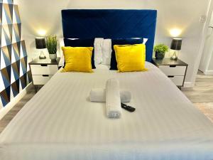 a white bed with yellow pillows and a blue headboard at Sleek Urban Getaway - With Parking in Bournemouth