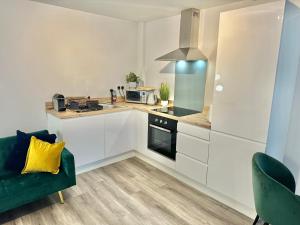 a kitchen with white cabinets and a green couch at Sleek Urban Getaway - With Parking in Bournemouth