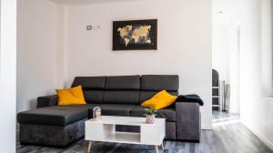 - un salon avec un canapé noir et des oreillers jaunes dans l'établissement Le Modernisme - Joli T3 lumineux pour 4 pers, à Poitiers
