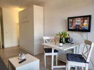 - un salon avec une table et une télévision murale dans l'établissement Apartment 35 im Haus Villa Anna, à Sankt Peter-Ording