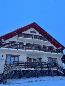 a house with a snow covered roof with a balcony at Pensiunea Irina Maramureș in Deseşti