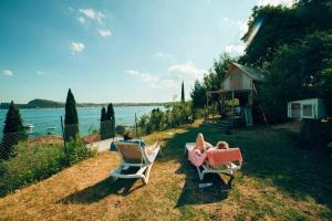 a couple of people sitting in lawn chairs next to the water at Vacanze Glamping Boutique in San Felice del Benaco