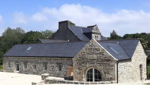 una antigua iglesia de piedra con techo negro en Gite de charme à la ferme 4 personnes, en Landrévarzec