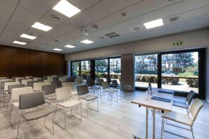 une salle de conférence avec des chaises, des tables et des fenêtres dans l'établissement Belstay Venezia Mestre, à Marghera