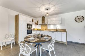 a kitchen with a table and chairs and a clock at View Point Trésumvibes - Appartement cosy, proche lac & vielle ville in Annecy