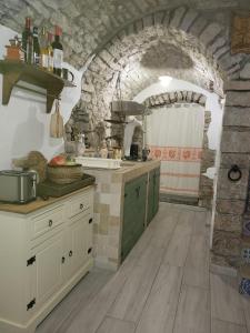 - une cuisine avec des placards blancs et un mur en pierre dans l'établissement Casa Eleonora, à Bosa