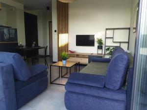 a living room with two blue couches and a tv at Apartament Burgund Wyspa Sobieszewska in Gdańsk