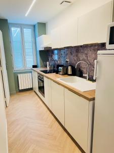 a kitchen with white cabinets and a wooden floor at Le Scandinave - PROCHE MACON - PARKING GRATUIT - NETFLIX in Pont-de-Veyle