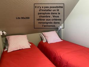 - deux lits rouges assis l'un à côté de l'autre dans une pièce dans l'établissement La mer vue d'en haut , duplex à la naturelle sur la côte d'opale, à Wimereux