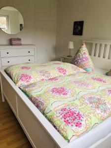 a bed with a floral comforter and a dresser at Ferienwohnung Am Kurpark 