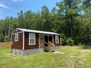 uma pequena casa com um alpendre num campo em Louisiana State Cabin em West Point