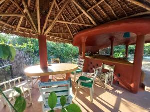 a patio with chairs and a table and a bar at Watamu Beach Cottages B&B in Watamu