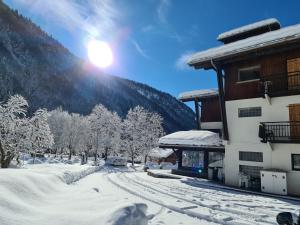 um edifício coberto de neve com o sol atrás dele em Hôtel Le Choucas em Sixt