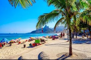 una playa con palmeras, sillas y el océano en Apartamento Studio Arpex HIR 25, en Río de Janeiro