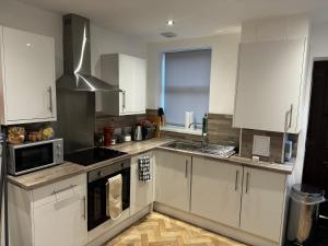 a kitchen with white cabinets and a microwave at Orionn Place in Nottingham