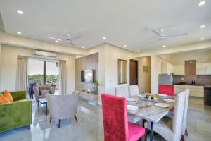 a dining room and living room with a table and chairs at Premium 2BHK Apartment with pool at Candolim Beach in Candolim