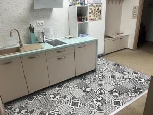 a kitchen with white cabinets and a black and white tile floor at Centrum Apartmán Armida in Bardejov