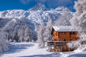a log cabin in the snow with mountains in the background at Spacious family chalet with balcony and garden in Chamonix
