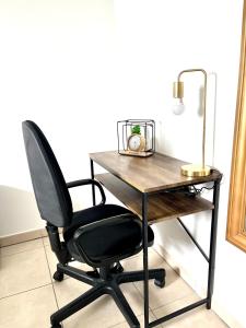 einen Schreibtisch mit einem Stuhl und einer Lampe in der Unterkunft Superbe appart avec Jardin à 2 min de l’Aéroport-4 pers in Vitrolles