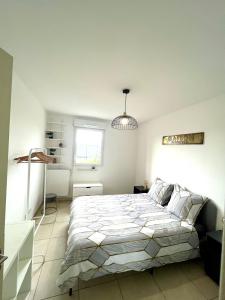 ein weißes Schlafzimmer mit einem großen Bett und einem Fenster in der Unterkunft Superbe appart avec Jardin à 2 min de l’Aéroport-4 pers in Vitrolles