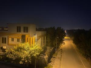 una calle vacía por la noche con una casa y árboles en Luxe Suites Bahria Town Lahore en Lahore