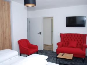 a hotel room with a red couch and two chairs at Das Haus am See in Sinzheim